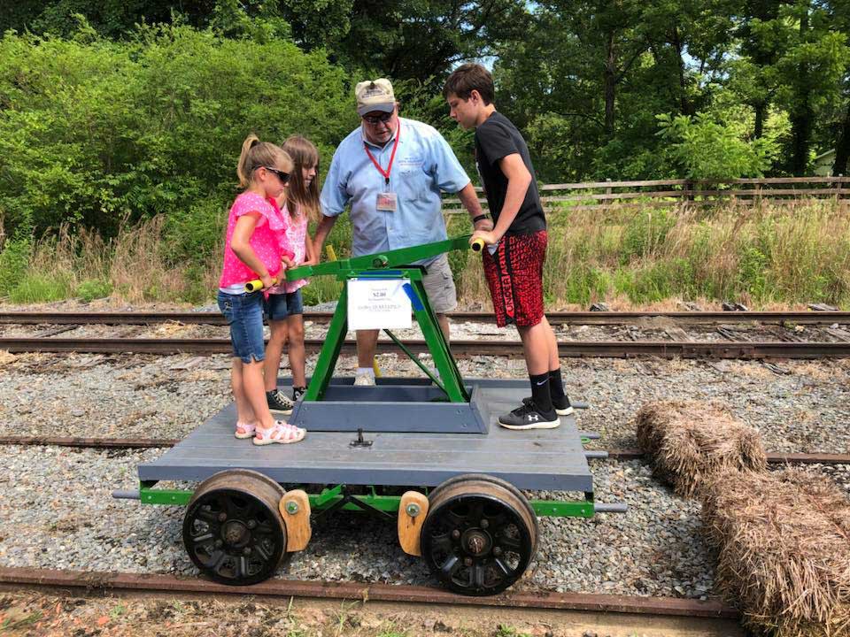 photo of two children an adult doing a railroad push-car